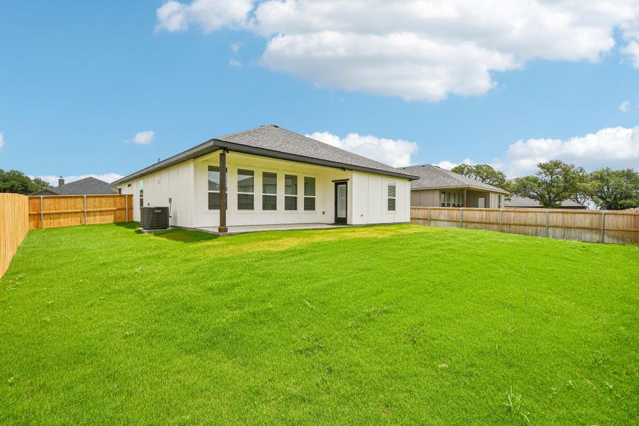 A vibrant green lawn extends from the back of this modern home, featuring a covered patio area and full fencing. A vibrant green lawn extends from the back of this modern home, featuring a covered patio area and full fencing.