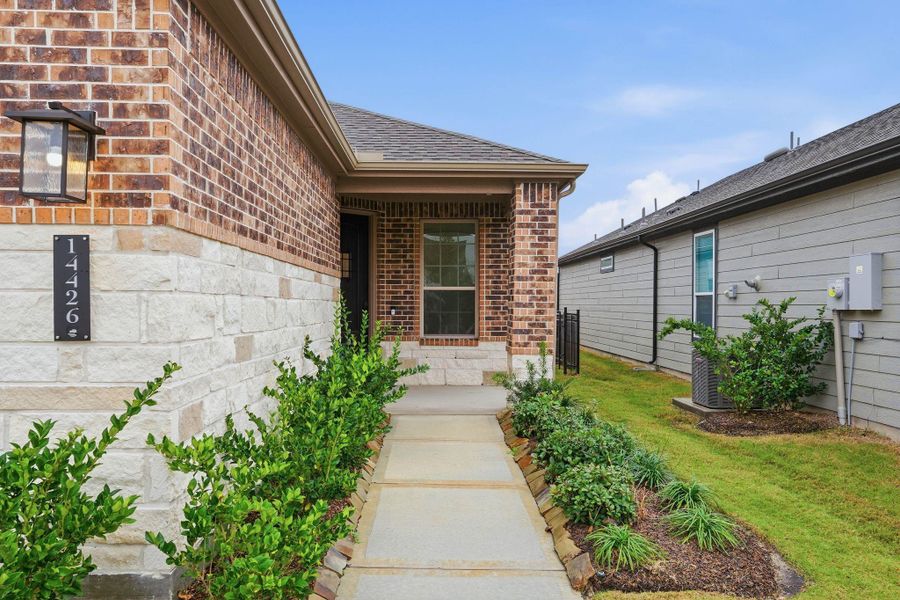 The front entrance welcomes you with a warm, inviting feel, framed by greenery along the walkway.