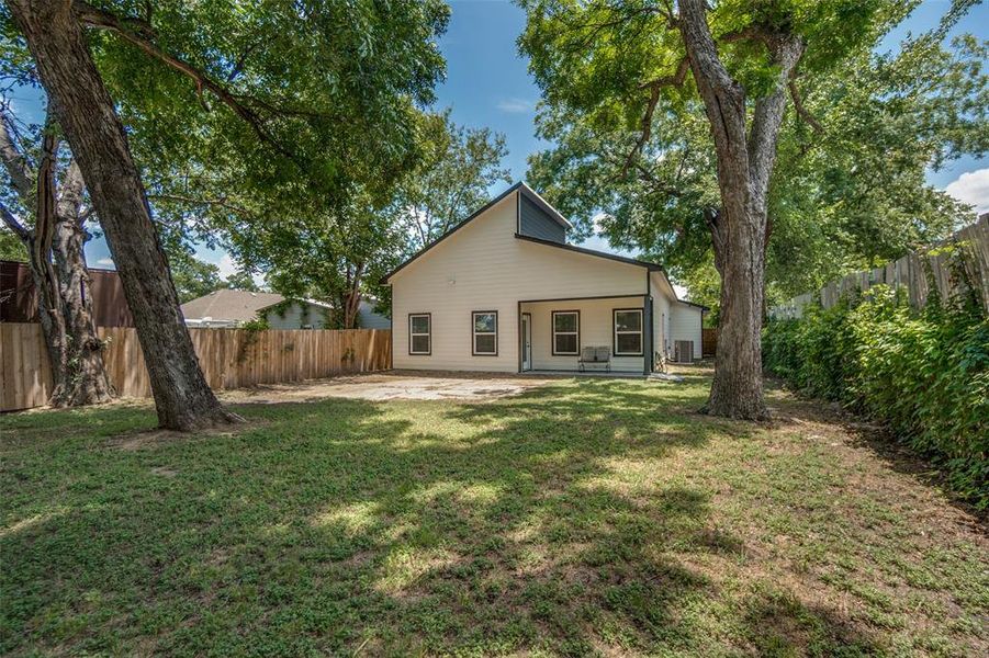 Spacious backyard featuring a manicured lawn, established shade trees, and a privacy fence Spacious backyard featuring a manicured lawn, established shade trees, and a privacy fence