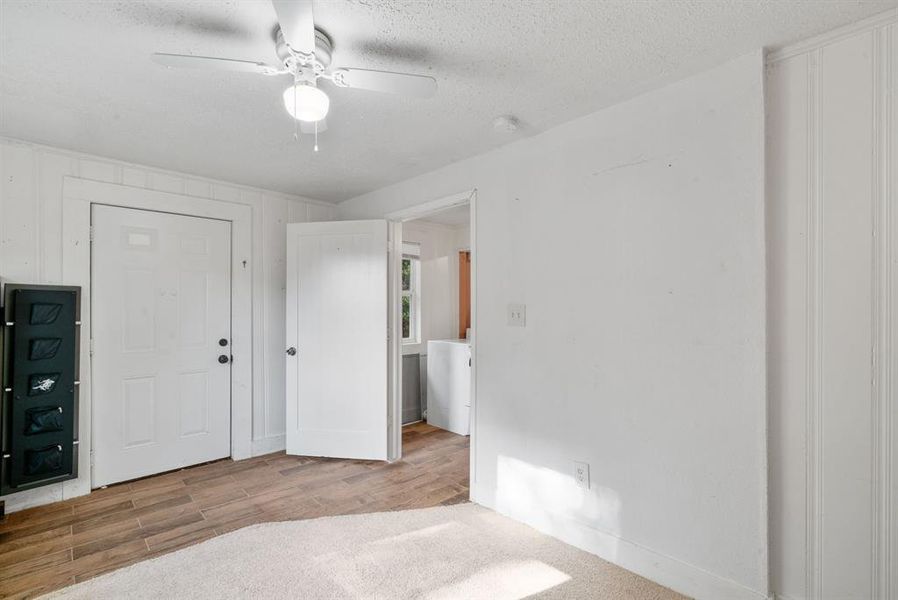 Unfurnished bedroom with light hardwood / wood-style flooring, ceiling fan, and a textured ceiling