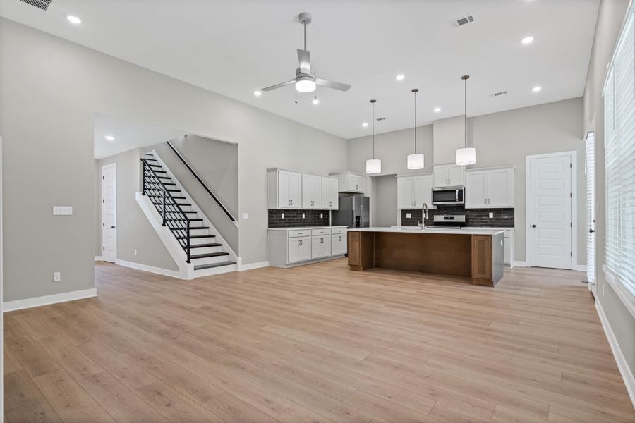 Expansive open-concept living area featuring light wood-finish flooring and high ceilings Expansive open-concept living area featuring light wood-finish flooring and high ceilings