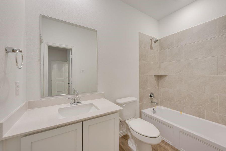 Full bathroom featuring vanity, tiled shower / bath, toilet, and hardwood / wood-style floors