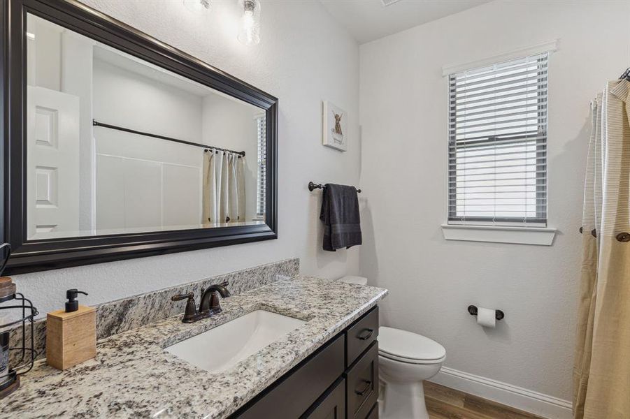 Bathroom featuring hardwood / wood-style floors, toilet, and vanity