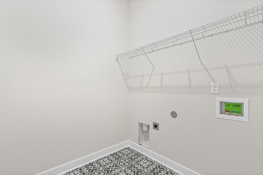 Utility space featuring patterned floor tile, crisp white baseboards, and a wire shelving unit Utility space featuring patterned floor tile, crisp white baseboards, and a wire shelving unit