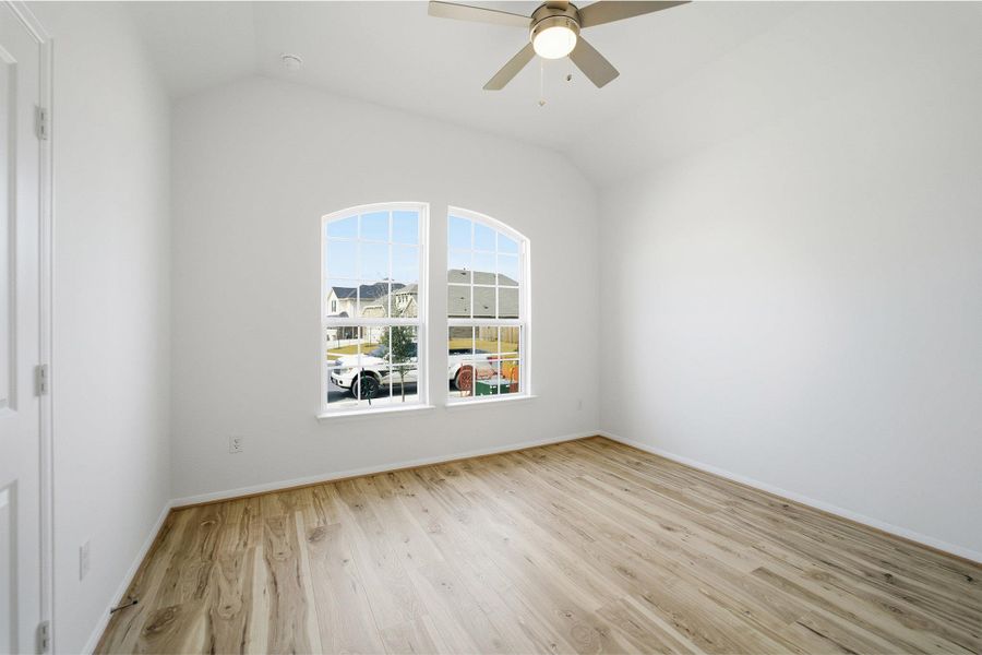 Unfurnished room featuring vaulted ceiling, light wood-style flooring, and ceiling fan