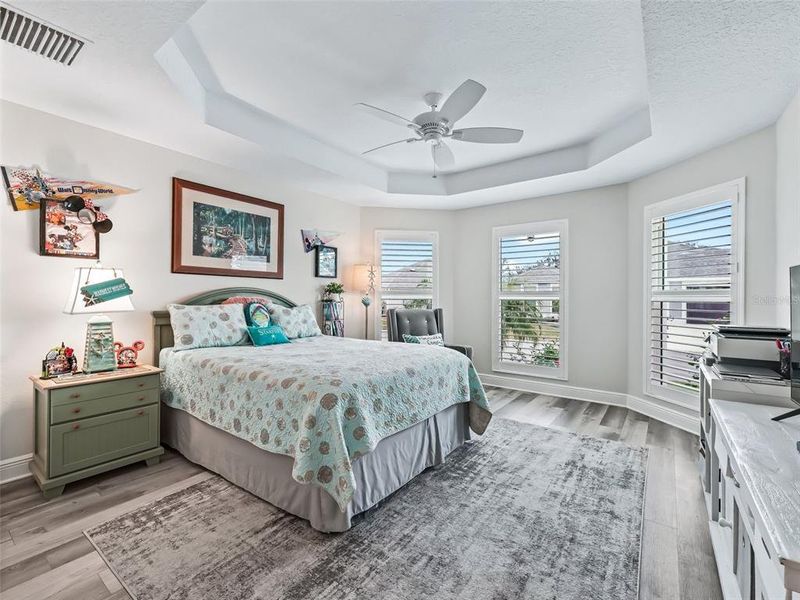 Front bedroom with coffered ceiling, bay windows, and plantation shutters