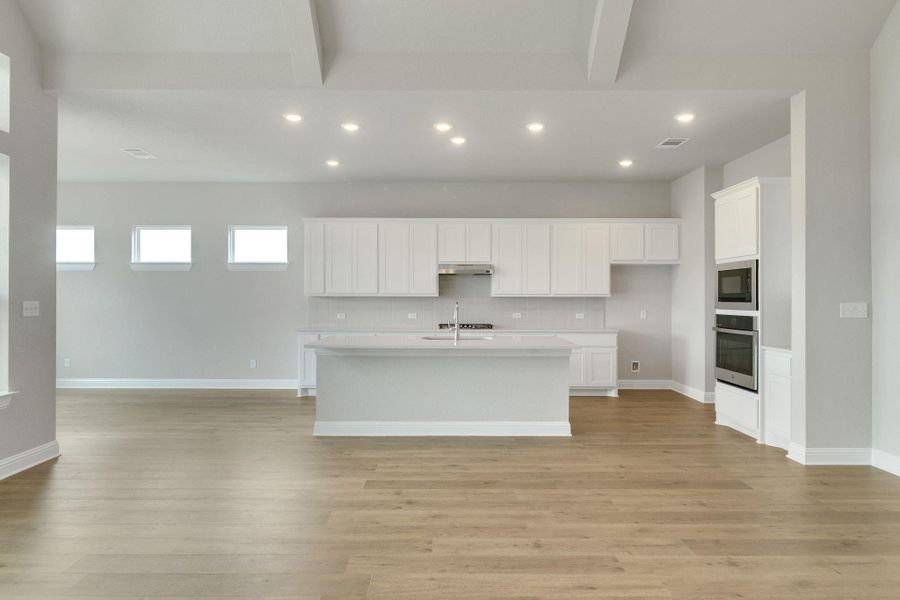 Kitchen featuring oven, open floor plan, recessed lighting, light countertops, and white cabinets