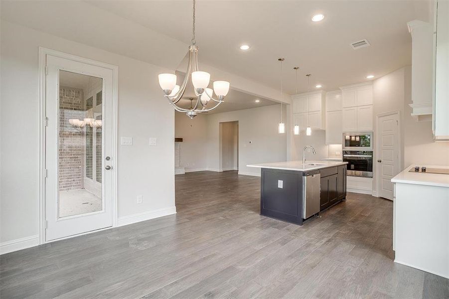 Kitchen featuring hardwood / wood-style floors, a kitchen island with sink, hanging light fixtures, stainless steel appliances, and sink