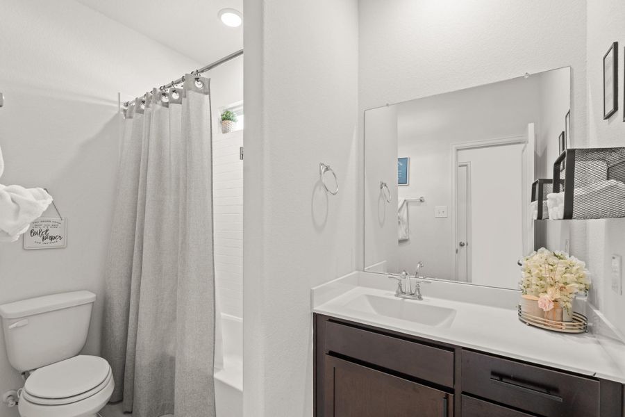 This full bathroom is located off the hall of the secondary bedrooms making it easy to share and get ready. It features an oversized vanity, wood cabinets, quartz countertops, and a combination tub and shower.