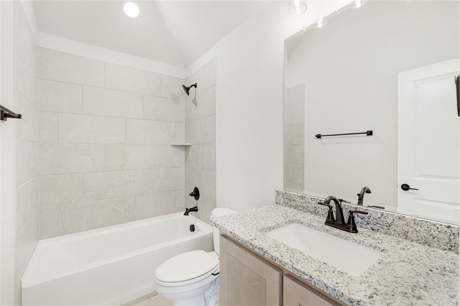 Bathroom with tiled tub-shower combo, granite countertop vanity, and dark bronze fixtures