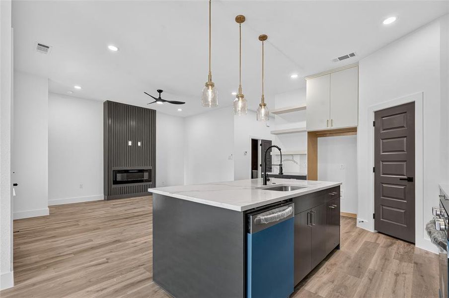 Open-concept living space featuring a kitchen island with pendant lighting, a built-in dishwasher, and a deep sink Open-concept living space featuring a kitchen island with pendant lighting, a built-in dishwasher, and a deep sink