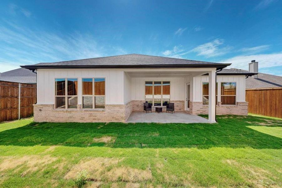 Back of house featuring board and batten siding, a patio, a fenced backyard, brick siding, and a shingled roof