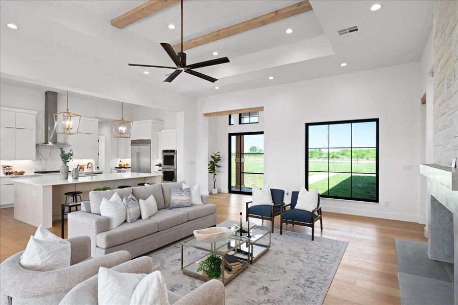 Living area with a towering ceiling, recessed lighting, a fireplace, light wood-style floors, and beamed ceiling