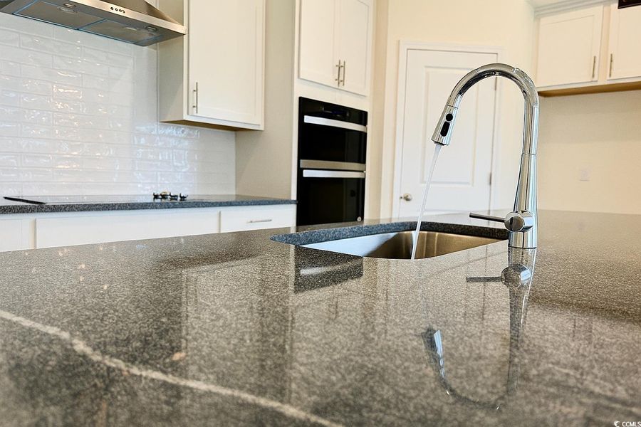 Kitchen with range hood, tasteful backsplash, and dark stone counters Kitchen with range hood, tasteful backsplash, and dark stone counters