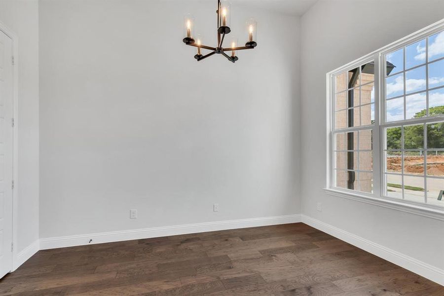 Spare room featuring an inviting chandelier and dark wood-type flooring