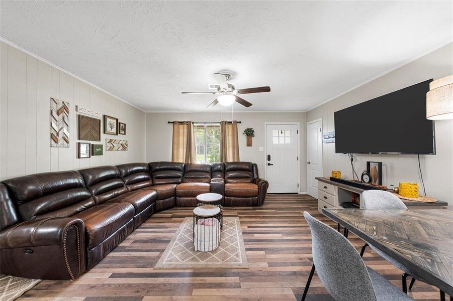 Living room featuring wood finished floors, ornamental molding, and ceiling fan Living room featuring wood finished floors, ornamental molding, and ceiling fan