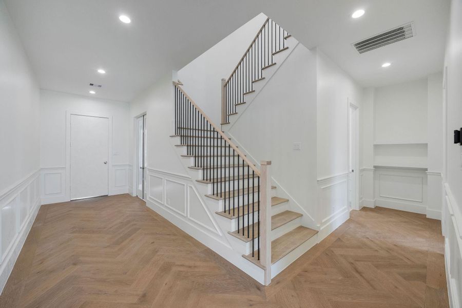 The grand entryway showcases herringbone wood floors and custom millwork, with a formal study by the main entrance. The grand entryway showcases herringbone wood floors and custom millwork, with a formal study by the main entrance.