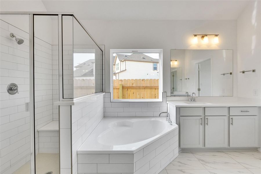 Full bathroom featuring a shower stall, vanity, a garden tub, and light marble finish flooring Full bathroom featuring a shower stall, vanity, a garden tub, and light marble finish flooring