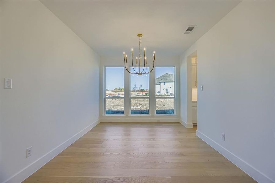 Unfurnished dining area featuring a chandelier and light wood finished floors