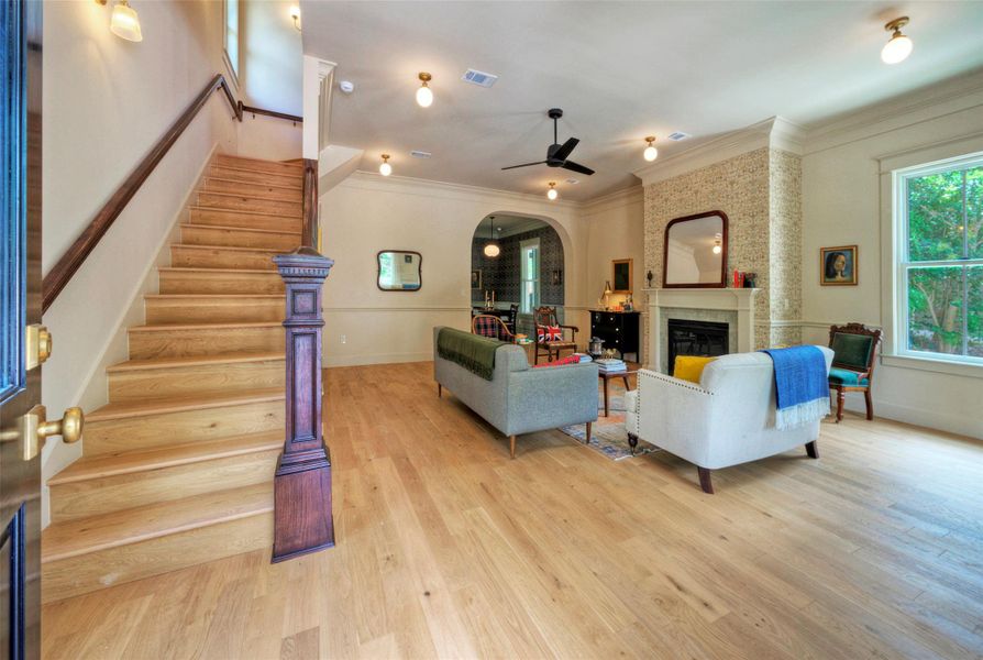 hardwood floors extend from the welcoming entry and staircase through a cozy living area with an elegant fireplace.