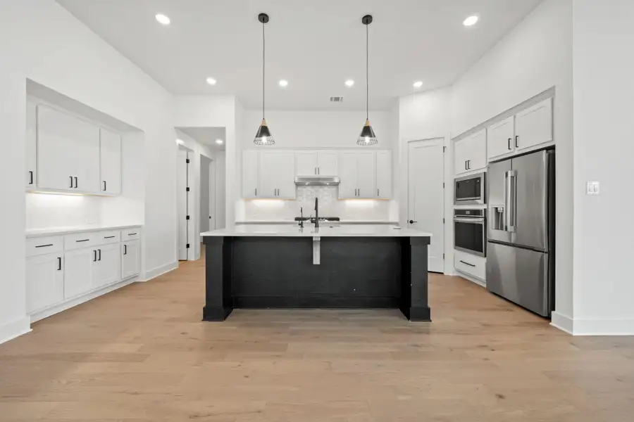 Kitchen featuring a kitchen breakfast bar, stainless steel appliances, pendant lighting, tasteful backsplash, and light wood-style floors
