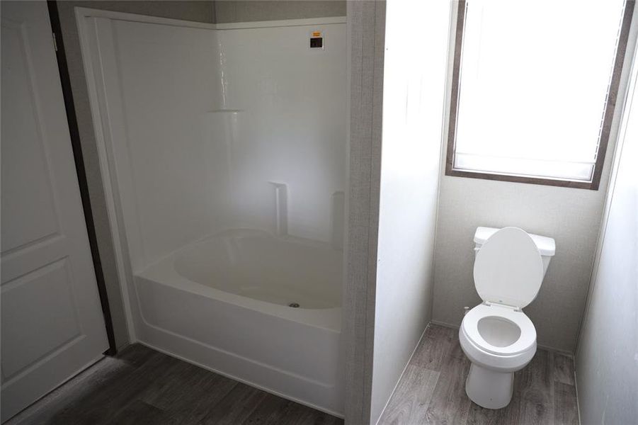 Bathroom with wood-type flooring, toilet, and shower / bathing tub combination