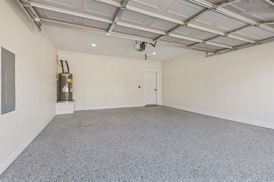 Garage with electric panel, electric water heater, and a garage door opener