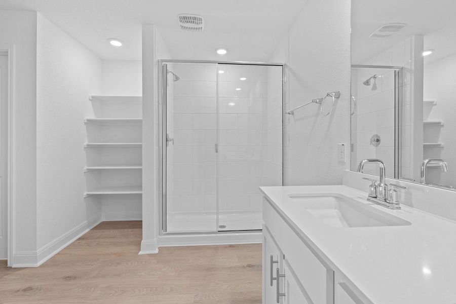 Full bath featuring vanity, light wood-style flooring, a spacious closet, and a shower stall Full bath featuring vanity, light wood-style flooring, a spacious closet, and a shower stall