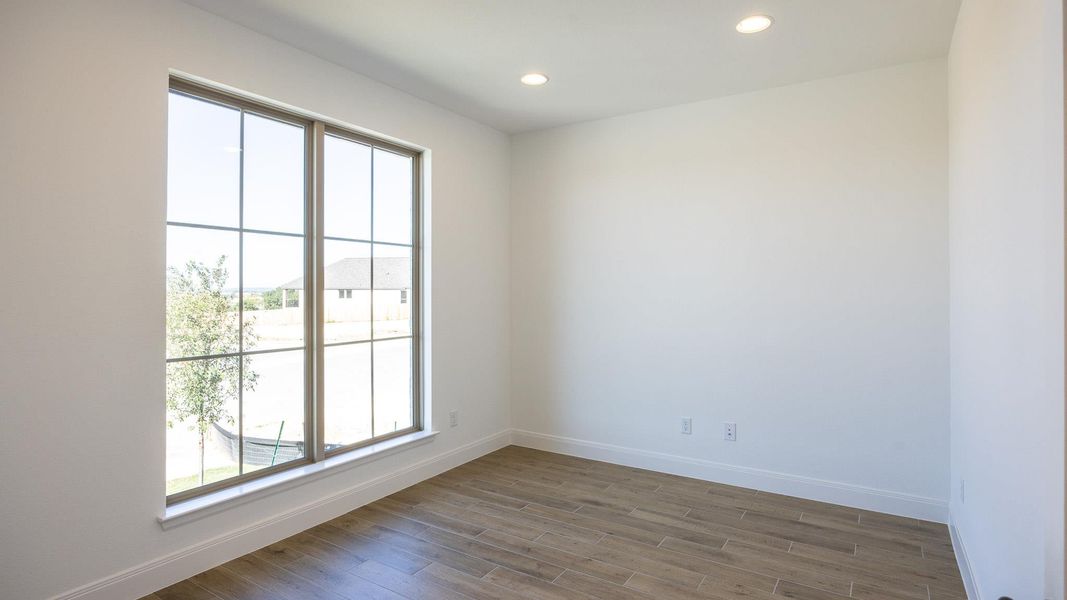 Empty room with recessed lighting, dark wood finished floors, and a water view