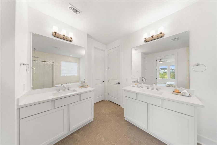 Ensuite bathroom with a shower stall, two vanities, light tile patterned flooring, and a ceiling fan Ensuite bathroom with a shower stall, two vanities, light tile patterned flooring, and a ceiling fan