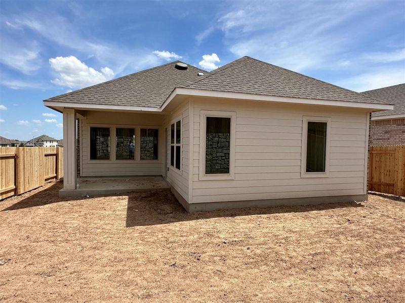Rear view of property featuring a fenced backyard, roof with shingles, and a patio area