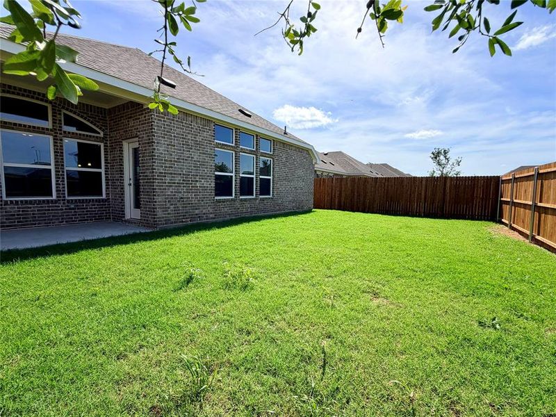 Expansive backyard featuring a manicured lawn, a full privacy fence, and a concrete patio