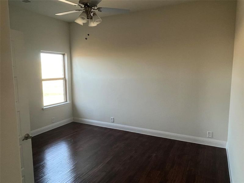 Unfurnished room with dark wood-type flooring and ceiling fan