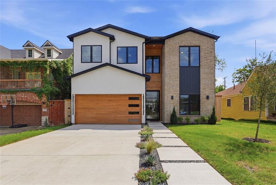 Contemporary exterior showcasing a stucco and brick facade with black-framed windows Contemporary exterior showcasing a stucco and brick facade with black-framed windows