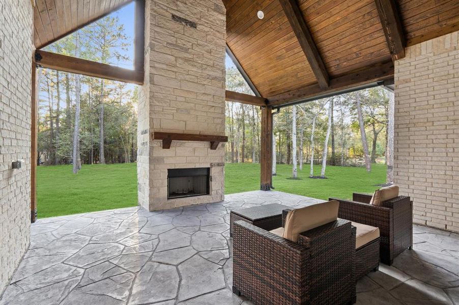 Covered patio featuring soaring high ceilings with recessed LED lights that create a bright and welcoming atmosphere, even at night. A stunning stone chimney adds warmth and charm, making it perfect for cozy evenings or hosting gatherings year-round.