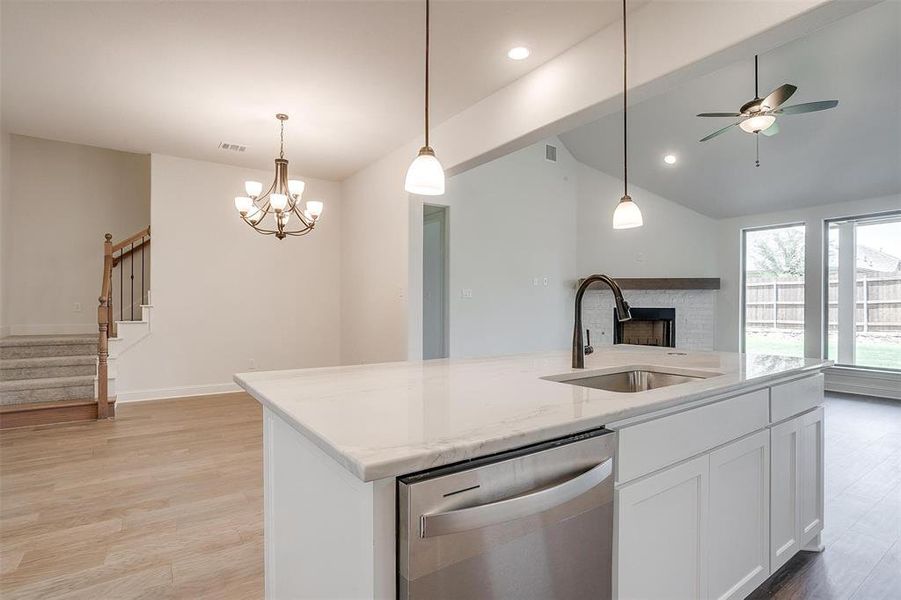 Kitchen featuring dishwasher, sink, a brick fireplace, and light hardwood / wood-style floors