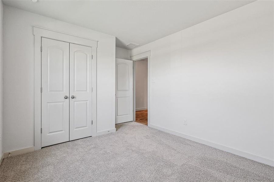 Unfurnished bedroom with light carpet and a closet