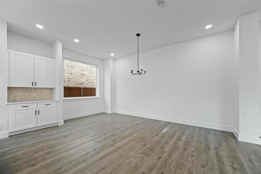 Unfurnished dining area featuring a chandelier, wood finished floors, and recessed lighting Unfurnished dining area featuring a chandelier, wood finished floors, and recessed lighting