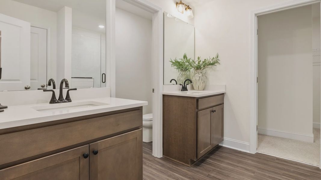 Townsend home plan en suite bathroom with separate vanities, tile shower, and ample closet storage