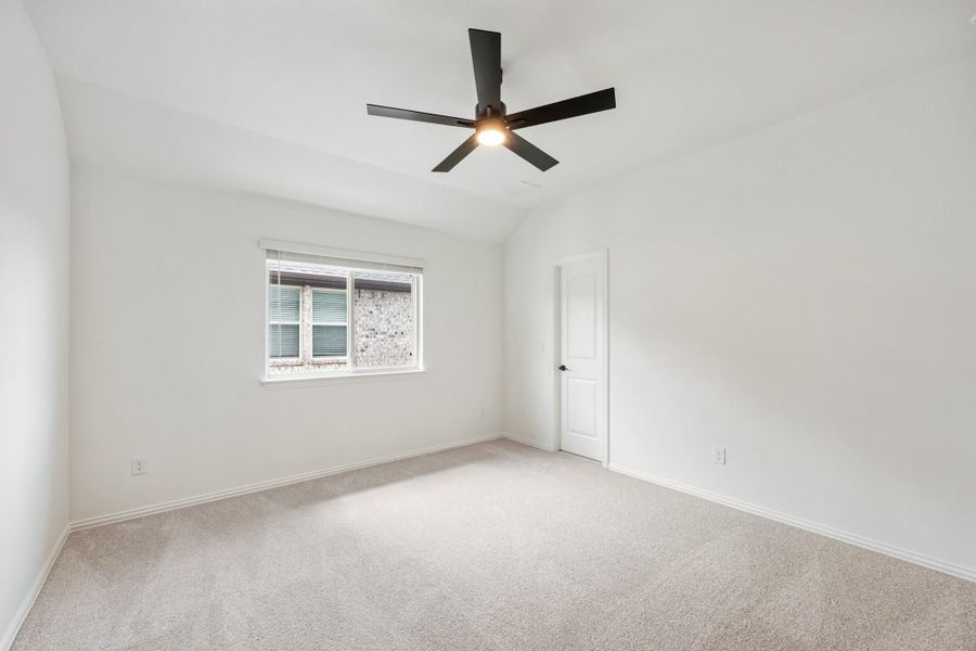 Empty bedroom with vaulted ceiling, black ceiling fan, carpet flooring, and a single window
