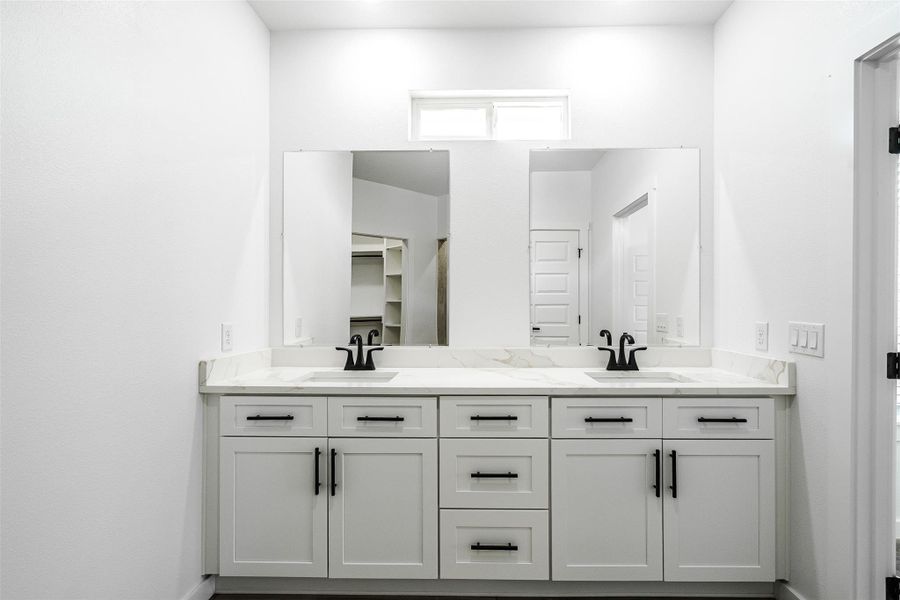 Double vanities with sleek black hardware and ample storage define this primary bathroom. Double vanities with sleek black hardware and ample storage define this primary bathroom.