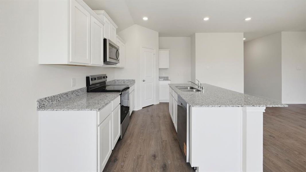 Kitchen with light stone countertops, appliances with stainless steel finishes, white cabinetry, and recessed lighting