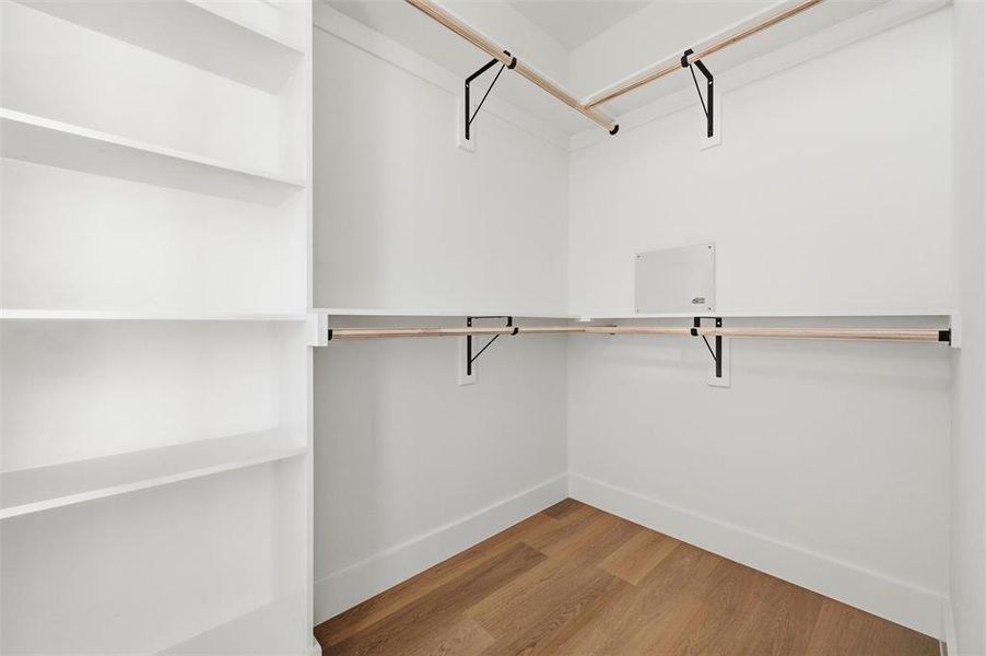 Primary Walk-In Closet features built-in shelving designed for organization and storage. Multiple
hanging rods extend throughout the space. Vinyl flooring extends throughout.