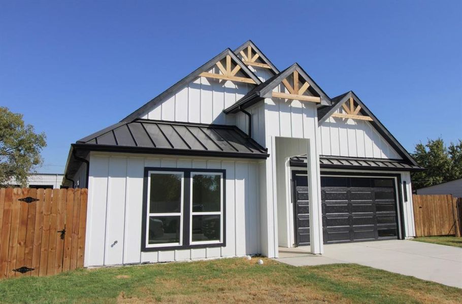 Modern inspired farmhouse featuring a standing seam roof, a metal roof, board and batten siding, and driveway Modern inspired farmhouse featuring a standing seam roof, a metal roof, board and batten siding, and driveway