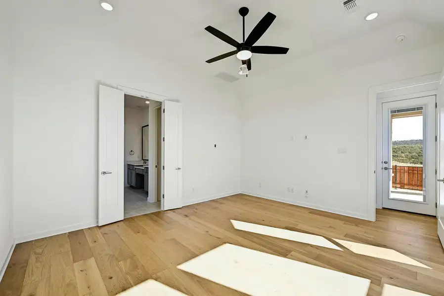 Unfurnished bedroom with access to outside, vaulted ceiling, light wood-style floors, ensuite bath, and recessed lighting