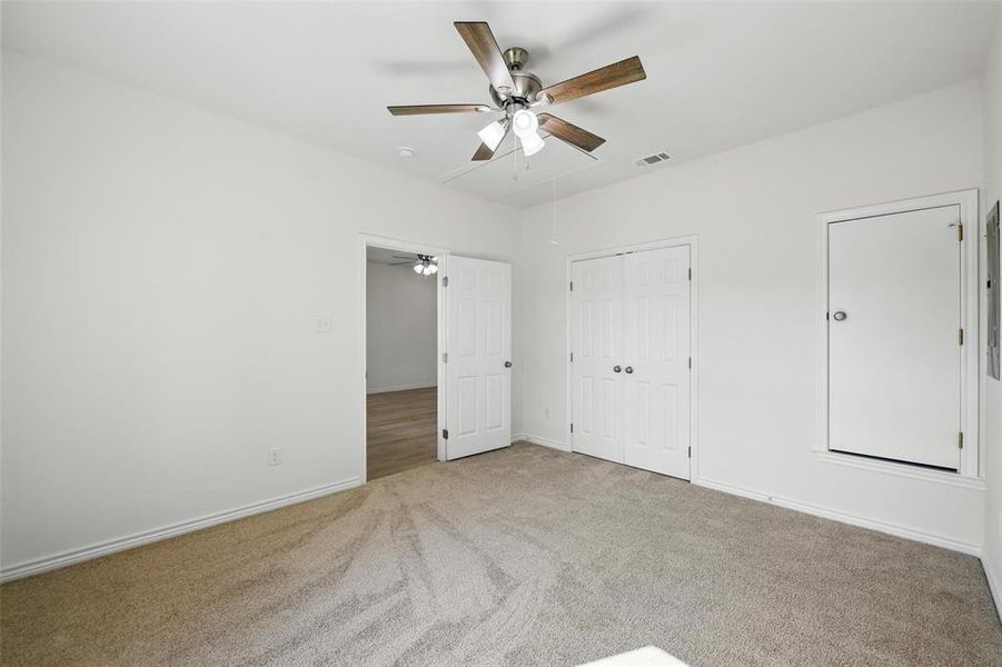Unfurnished bedroom featuring attic access, carpet flooring, baseboards, ceiling fan, and a closet Unfurnished bedroom featuring attic access, carpet flooring, baseboards, ceiling fan, and a closet