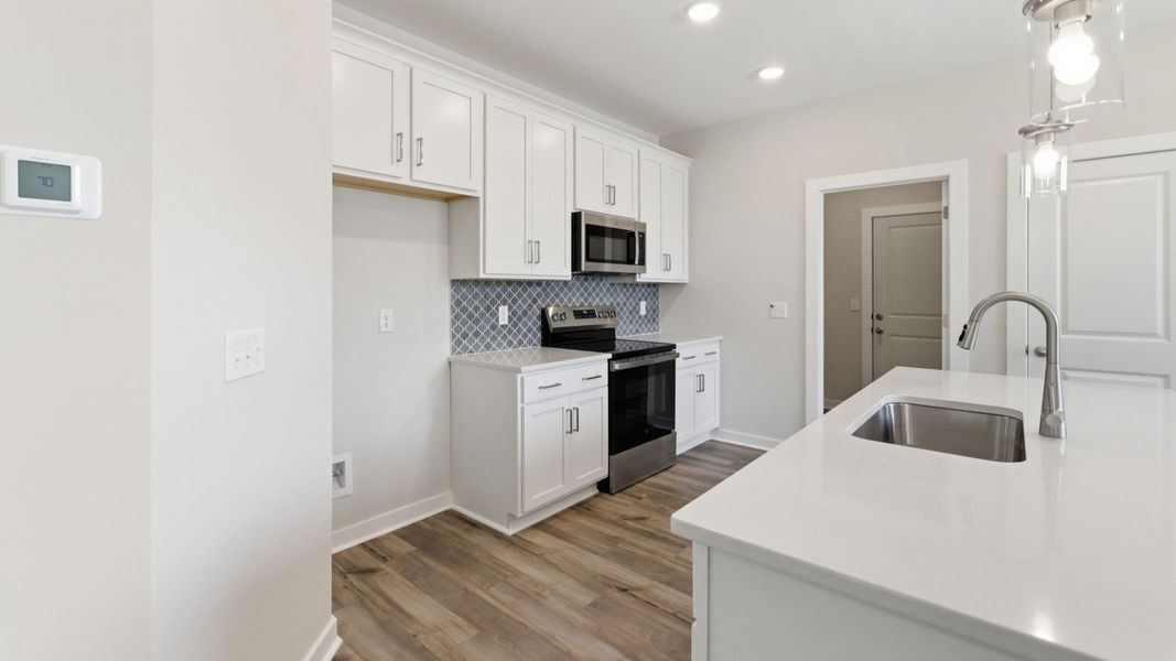 Kitchen with tile backsplash, pendant lighting, and quartz countertops Kitchen with tile backsplash, pendant lighting, and quartz countertops