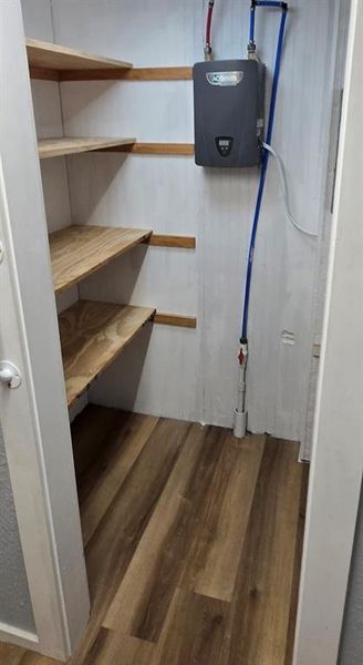 Kitchen with electric range, white cabinetry, light countertops, under cabinet range hood, and dark wood-type vinyl flooring.