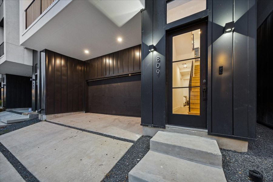 Contemporary exterior with a private driveway, oversized two-car garage, and a striking glass-front entry showcasing sleek architectural lines.