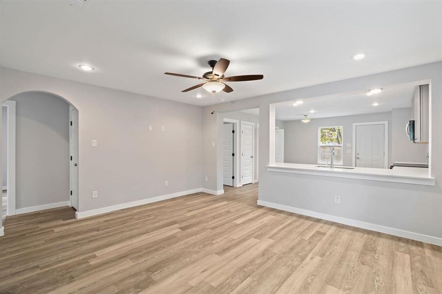 Unfurnished living room with light hardwood / wood-style flooring, sink, and ceiling fan